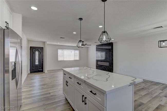 Kitchen featuring stainless steel fridge, open floor plan, light wood-style flooring, recessed lighting, and white cabinetry | Image 13