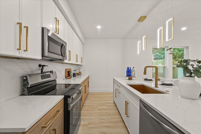 Kitchen featuring appliances with stainless steel finishes, a sink, light wood-type flooring, tasteful backsplash, and light countertops | Image 6