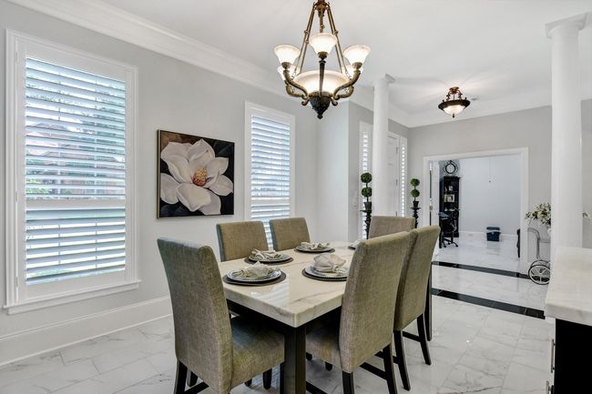 Dining area with light marble finish floors, decorative columns, ornamental molding, and a chandelier | Image 6