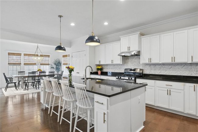 Gourmet kitchen seamlessly connected to the great room, featuring white cabinetry, granite countertops, stainless steel appliances, and a spacious island with pendant lighting. Open-concept layout provides a perfect flow for entertaining and everyday living. | Image 16
