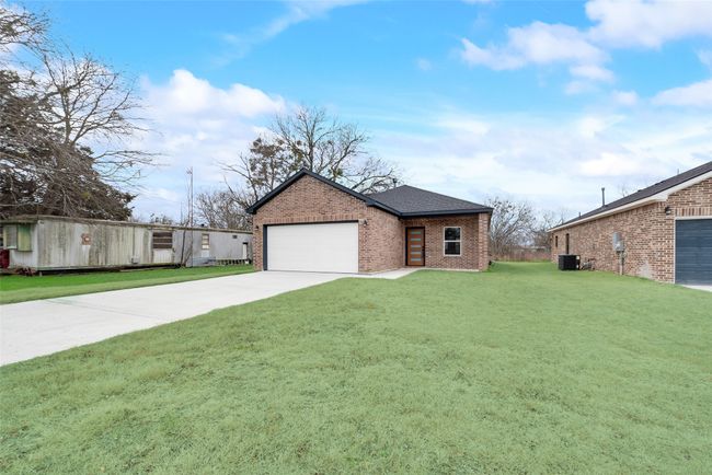 View of front facade featuring brick siding, concrete driveway, a front yard, an attached garage, and a shingled roof | Image 30