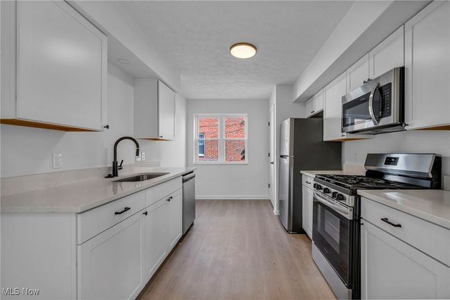 Kitchen featuring white cabinets, light countertops, a sink, and appliances with stainless steel finishes | Image 8
