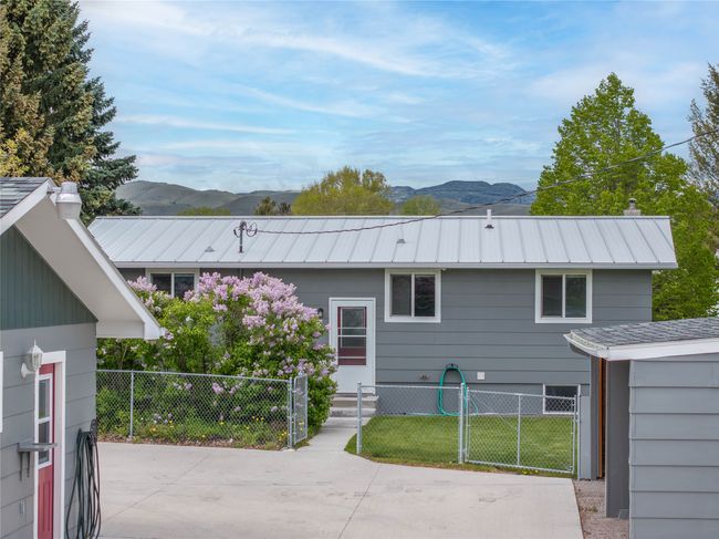 Rear view of property featuring a mountain view, a gate, metal roof, and a chimney | Image 7
