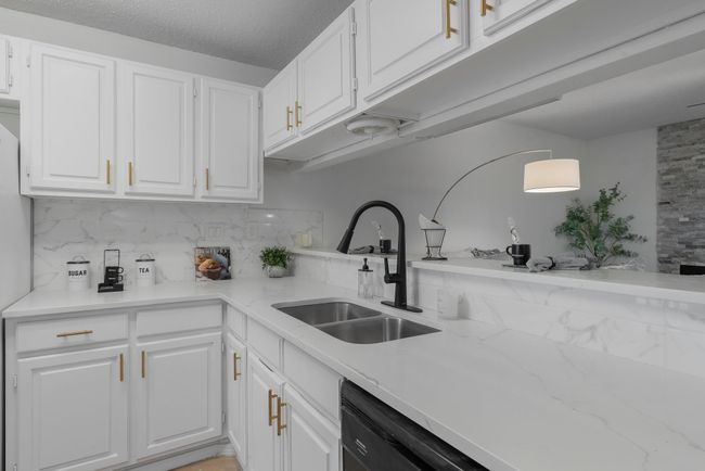 Kitchen featuring white cabinets, a sink, backsplash, and black dishwasher | Image 22