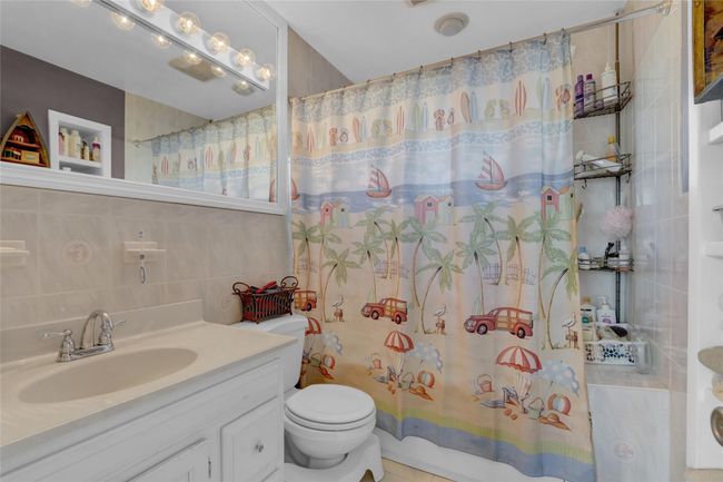Bathroom with tile walls, decorative backsplash, vanity, and toilet | Image 22