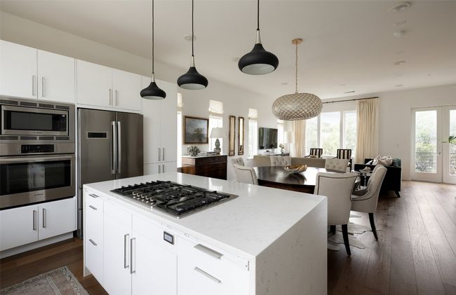 Kitchen featuring appliances with stainless steel finishes, open floor plan, dark wood finished floors, and decorative light fixtures | Image 11