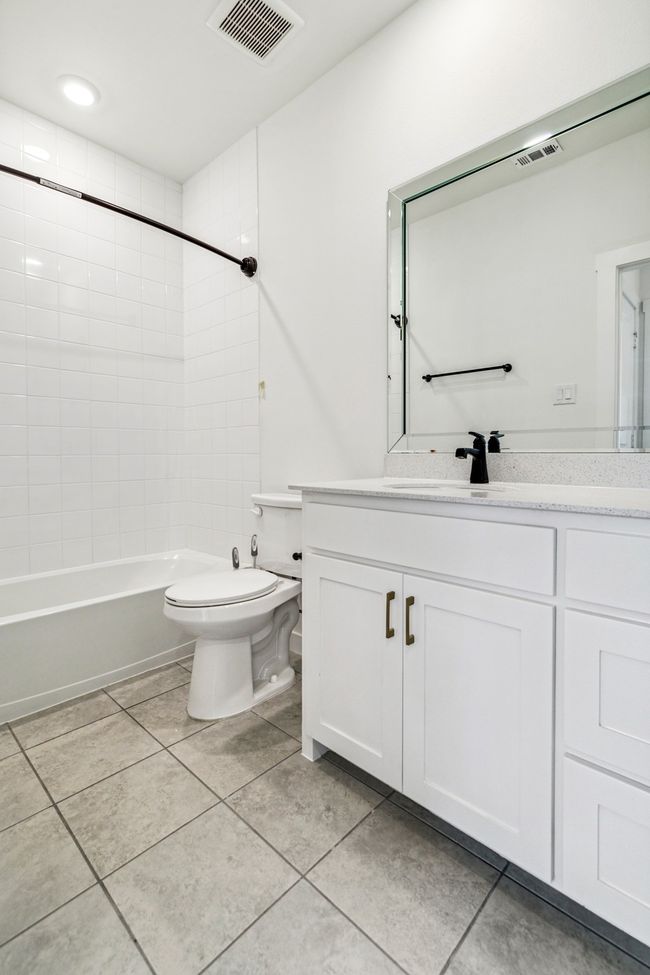 Full bathroom featuring vanity, tile patterned flooring, toilet, and washtub / shower combination | Image 28
