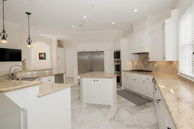The functional island kitchen with granite counters has a gas cooktop, dual ovens with vent hood and huge built-in refrigerator | Image 12
