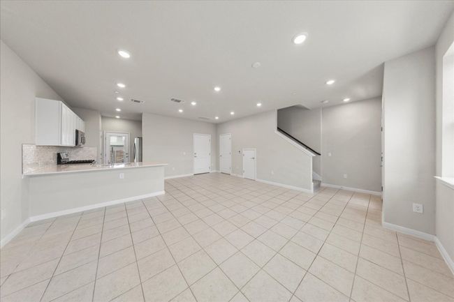 Unfurnished living room with recessed lighting, baseboards, light tile patterned floors, and stairway | Image 5