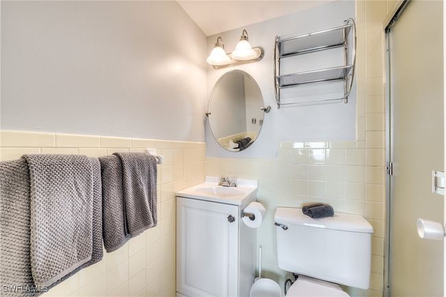 Bathroom with tile walls, vanity, toilet, and an enclosed shower | Image 11