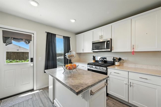 Kitchen featuring stainless steel appliances, light wood-style floors, white cabinetry, a center island, and recessed lighting | Image 12