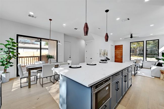 Kitchen with ceiling fan, decorative light fixtures, light stone countertops, a center island, and light hardwood / wood-style floors | Image 9