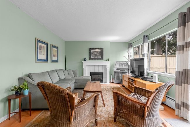 Living area featuring baseboards, a textured ceiling, wood finished floors, and a fireplace | Image 5