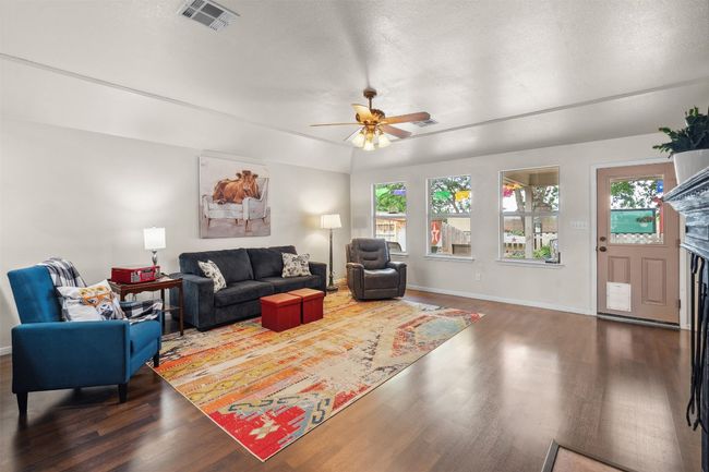 Living room with wood finished floors, visible vents, a ceiling fan, and a healthy amount of sunlight | Image 7