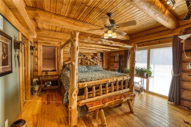 Bedroom with access to exterior, beamed ceiling, wood ceiling, hardwood / wood-style flooring, and rustic walls | Image 19