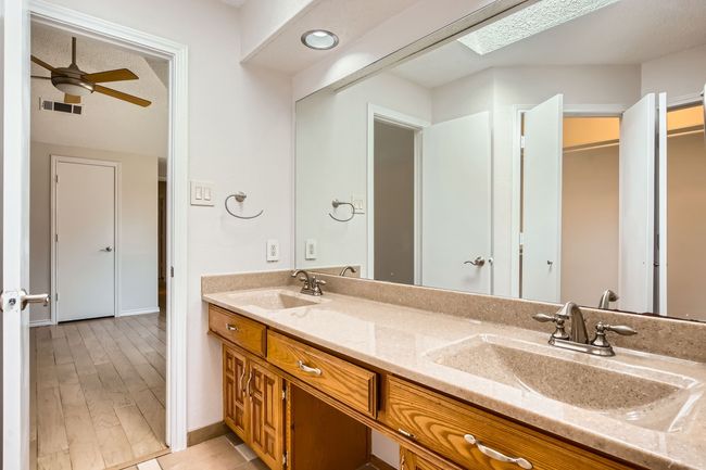 Bathroom featuring double vanity, a ceiling fan, and a skylight | Image 16