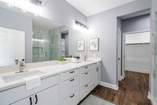 Full bath with a marble finish shower, double vanity, wood finished floors, a walk in closet, and baseboards | Image 16