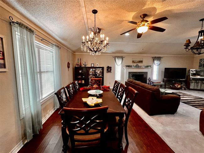 Dining area with a textured ceiling, dark wood-type flooring, ceiling fan with notable chandelier, and ornamental molding | Image 17