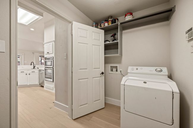 Washroom with light wood-style flooring, a sink, washer / dryer, and laundry area | Image 19