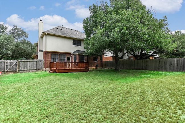 Back of house featuring brick siding, a chimney, a wooden deck, and a shingled roof | Image 19