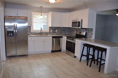 Kitchen featuring pendant lighting, sink, white cabinets, and stainless steel appliances | Image 2