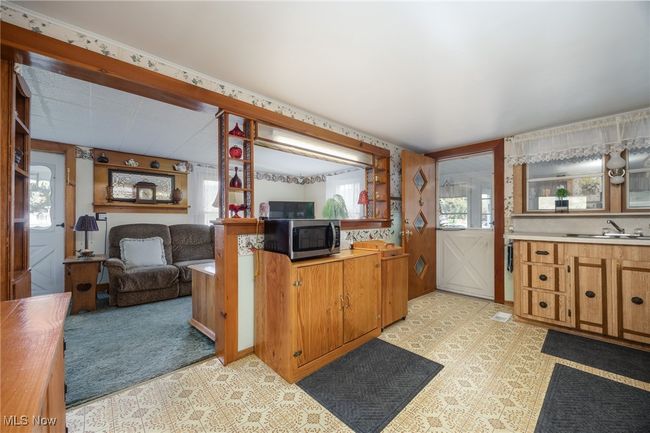 Kitchen with brown cabinetry, a sink, light countertops, and stainless steel microwave | Image 10