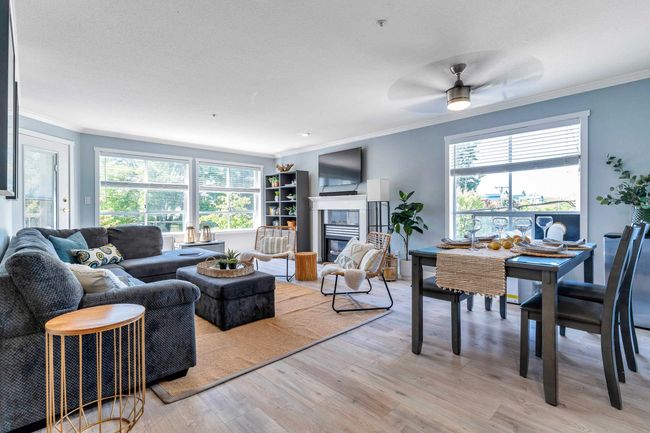 Living area featuring light wood-type flooring, plenty of natural light, a fireplace, and crown molding | Image 6