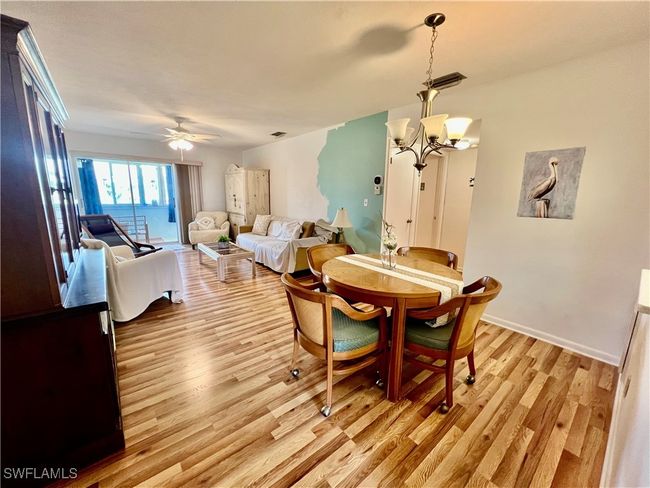 Dining area with light wood-style floors, visible vents, baseboards, and ceiling fan with notable chandelier | Image 12