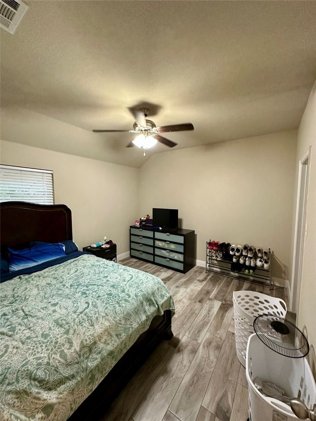 Bedroom featuring light wood-style flooring, a textured ceiling, and a ceiling fan | Image 25