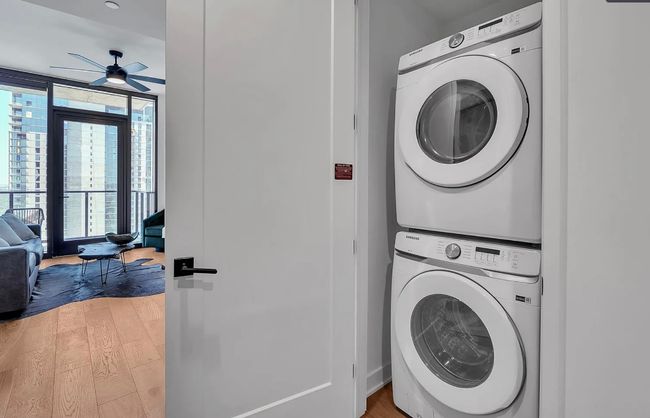 Laundry room featuring stacked washing machine and dryer, ceiling fan, and light wood-style floors | Image 14