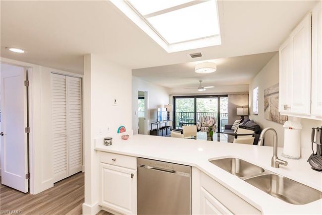Kitchen with white cabinets, stainless steel dishwasher, a sink, light wood-type flooring, and light countertops | Image 12