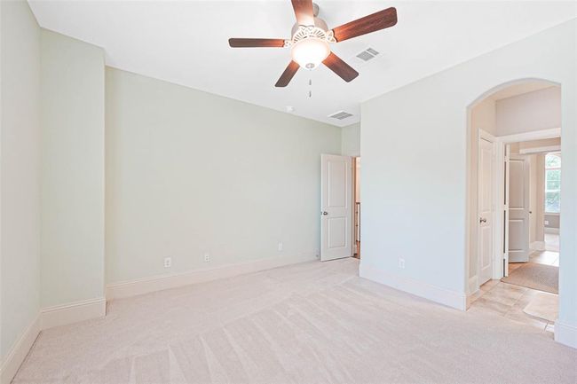 Bright and spacious secondary bedroom with plush carpeting, ceiling fan, and soft neutral tones. Features direct access to an en-suite or Jack-and-Jill bath, offering privacy and convenience. | Image 35