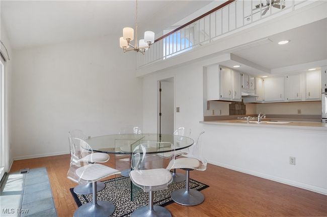 Dining area featuring a chandelier, light wood-style floors, baseboards, a high ceiling, and visible vents | Image 19