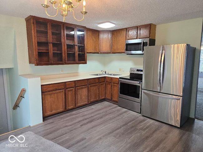 kitchen featuring a sink, a notable chandelier, appliances with stainless steel finishes, and wood finished floors | Image 12