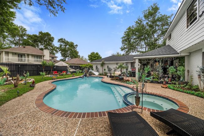 This backyard features a spacious pool with a stone deck | Image 24