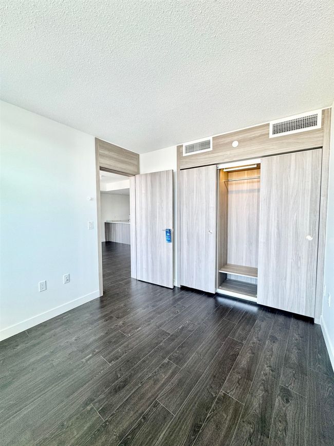 Spare room with a textured ceiling, baseboards, visible vents, and dark wood-style floors | Image 10