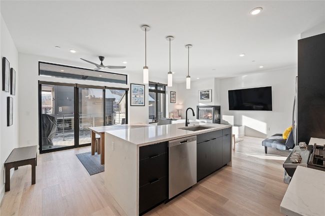 Kitchen featuring dishwasher, sink, decorative light fixtures, a kitchen island with sink, and light wood-type flooring | Image 4