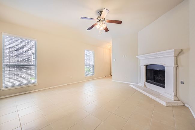 Unfurnished living room featuring ceiling fan, a fireplace with raised hearth, and light tile patterned floors | Image 4