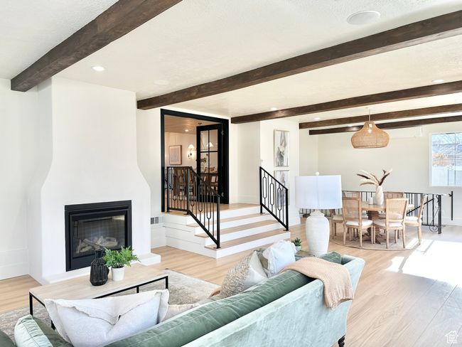 Living room with beamed ceiling, light wood-style flooring, a glass covered fireplace, and recessed lighting | Image 15