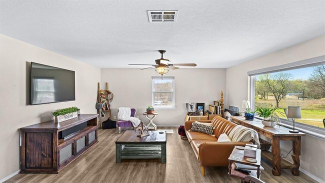 Living room featuring plenty of natural light, visible vents, wood finished floors, and ceiling fan | Image 30