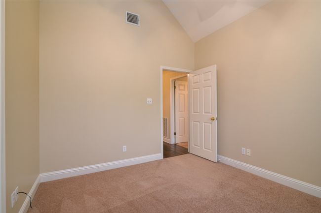 Carpeted empty room featuring baseboards and high vaulted ceiling | Image 11