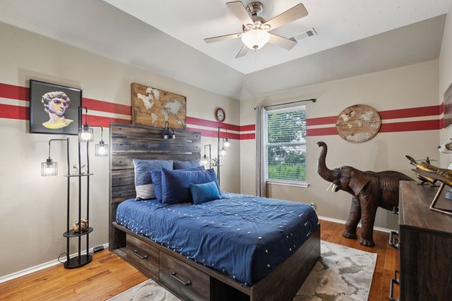 Bedroom featuring wood finished floors, baseboards, ceiling fan, and lofted ceiling | Image 24