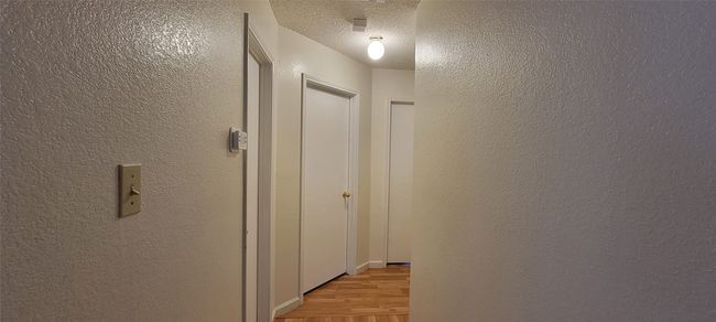 Corridor featuring light wood-style flooring, a textured wall, and a textured ceiling | Image 13