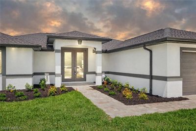 Exterior entry at dusk with french doors, a garage, and a lawn | Image 2