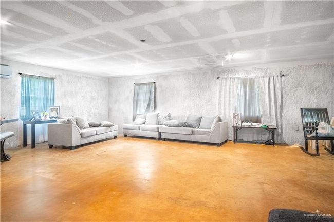 Living area featuring concrete floors and a wall mounted air conditioner | Image 5