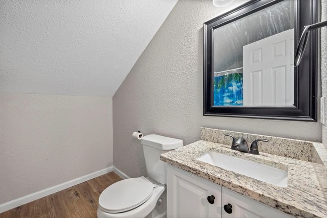 Hall Bathroom with lofted ceiling, wood finished floors, toilet, vanity, and baseboards | Image 8