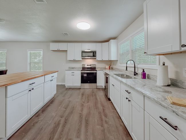 Kitchen with appliances with stainless steel finishes, healthy amount of natural light, light wood-type flooring, and white cabinetry | Image 17