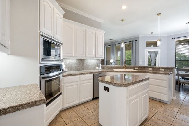Kitchen featuring appliances with stainless steel finishes, a center island, a peninsula, tasteful backsplash, and tile counters | Image 16