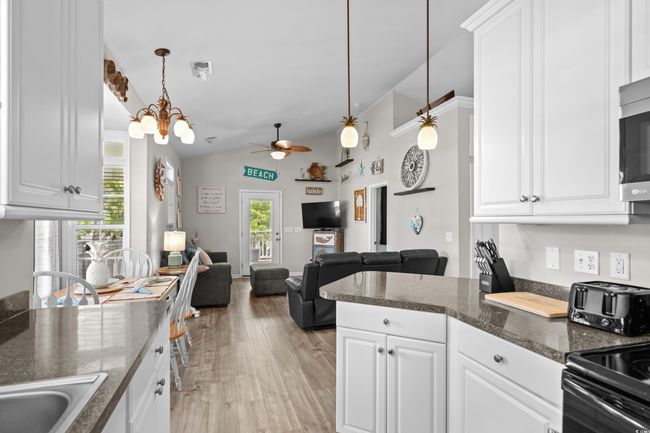 Kitchen with dark countertops, stainless steel dishwasher, white cabinetry, and a sink | Image 27
