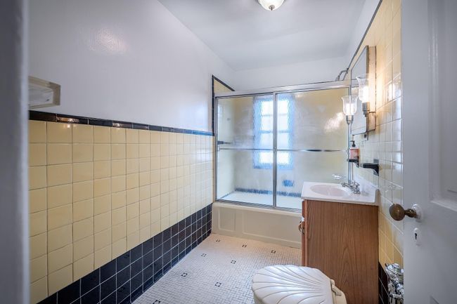 Bathroom with bath / shower combo with glass door, vanity, tile patterned flooring, and tile walls | Image 10